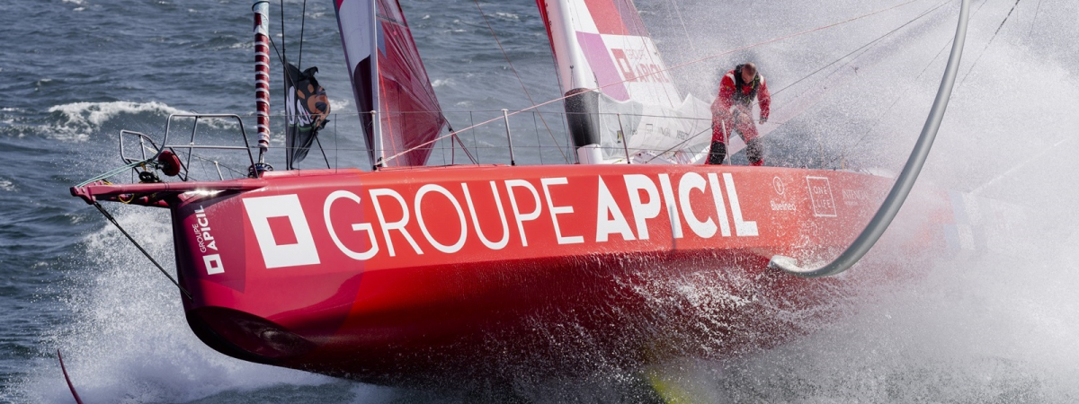 Silhouette lointaine d'un skippeur à bord d'un monocoque de course au large au large volant sur l'océan